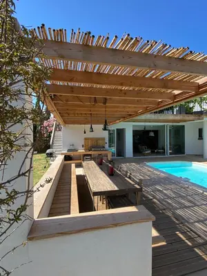 a wooden patio with a table and a wooden pergola at Villa bord de mer avec piscine 200 métres plage in Zonza