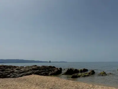 a beach with some rocks in the water at Proche porticcio, Coup de cœur asuré,Appartement de standing, rez de villa 6 couchages, climatisé à 150m de la plage, terrains de tennis in Grosseto-Prugna