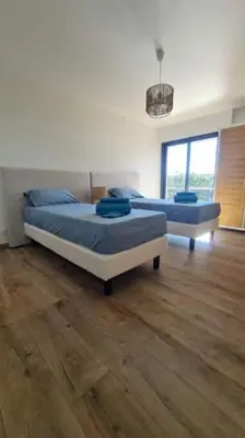 two beds in a room with wooden floors at Proche porticcio, Coup de cœur asuré,Appartement de standing, rez de villa 6 couchages, climatisé à 150m de la plage, terrains de tennis in Grosseto-Prugna