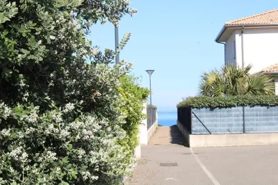 a sidewalk next to a house with the ocean in the background at Maison T3, 50m de la mer, cadre reposant in Santa-Lucia-di-Moriani