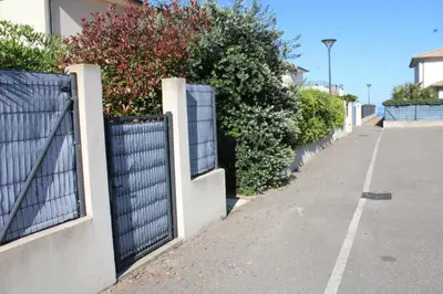 a fence next to a sidewalk with bushes at Maison T3, 50m de la mer, cadre reposant in Santa-Lucia-di-Moriani