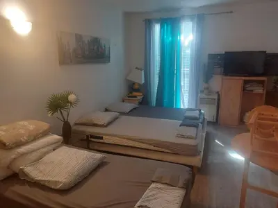 a bedroom with two beds and a window with blue curtains at AJACCIO Beau Studio pour 3 a 4 pers en Plein Centre de la Vieille Ville Historique in Ajaccio