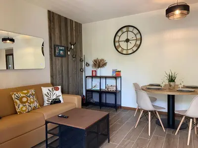 a living room with a couch and a table and a clock at Villa luxury vue mer à 300m du centre ville terrasse,jardin,parking privé in Porto-Vecchio