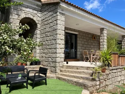 a stone house with a patio and a table and chairs at Villa luxury vue mer à 300m du centre ville terrasse,jardin,parking privé in Porto-Vecchio
