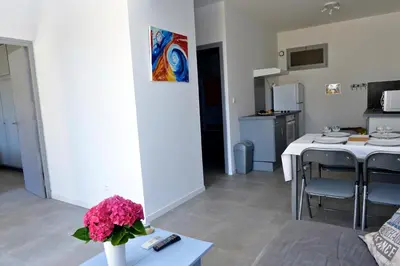 a living room and kitchen with a table and flowers at Corsicadream Barbicaja, superbe appartement dans villa, vue panoramique mer, piscine, proche Porticcio in Pietrosella