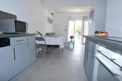 a kitchen with white appliances and a table with a dining room at Corsicadream Barbicaja, superbe appartement dans villa, vue panoramique mer, piscine, proche Porticcio in Pietrosella