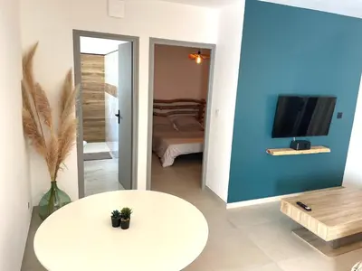 a living room with a white table and a tv at Mini maison entre mer et montagne in Aléria