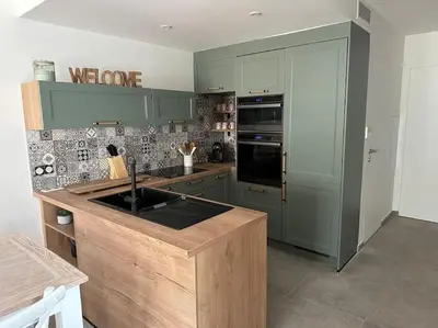 a kitchen with green cabinets and a counter top at Duplex avec piscine, près de la mer, Cala Rossa in Lecci