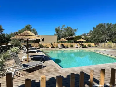 a swimming pool with chairs and umbrellas on a deck at Duplex avec piscine, près de la mer, Cala Rossa in Lecci