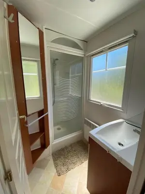a bathroom with a sink and a shower with a window at Mobil Home in Tralonca