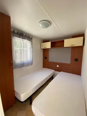 a small room with two beds and a window at Mobil Home in Tralonca