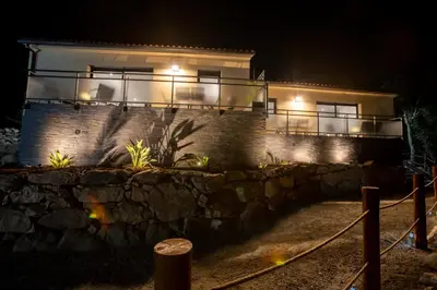 a house at night with a stone wall and lights at Casa Emma in Sollacaro