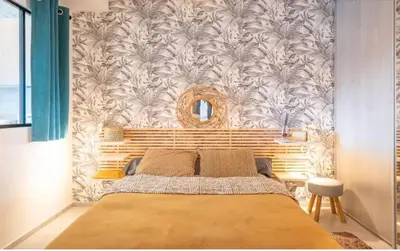 a bedroom with a bed and a wall with a mirror at Appartement moderne à Ajaccio de 45 m² avec terrasse vue mer in Ajaccio