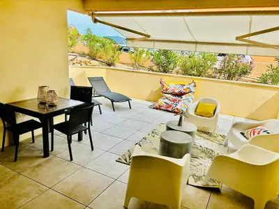 a patio with a table and chairs and a couch at Appartement moderne à Ajaccio de 45 m² avec terrasse vue mer in Ajaccio