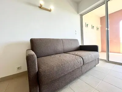 a couch sitting in a room with a window at Studio Cosy à 50m de la plage avec Parking - Résidence ARIA MARINA route des sanguinaires in Ajaccio