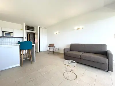 a living room with a couch and a kitchen at Studio Cosy à 50m de la plage avec Parking - Résidence ARIA MARINA route des sanguinaires in Ajaccio