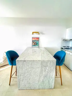 a kitchen with a marble table and two blue chairs at Studio Cosy à 50m de la plage avec Parking - Résidence ARIA MARINA route des sanguinaires in Ajaccio