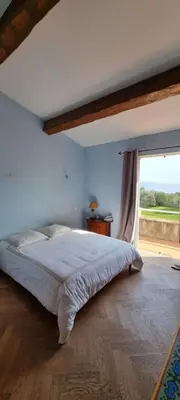 a bedroom with a large bed with a large window at Maison accès direct plage corse du sud in Coti-Chiavari