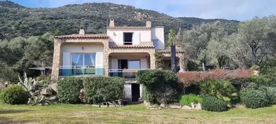 a large house with a mountain in the background at Maison accès direct plage corse du sud in Coti-Chiavari