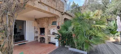 a house with a courtyard with a stone wall at Maison accès direct plage corse du sud in Coti-Chiavari