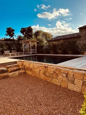 a swimming pool with a stone wall next to a house at bergerie-ucaseddu in Zonza