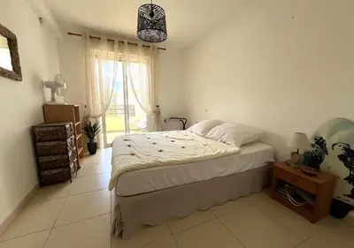 a bedroom with a bed and a large window at MORIANI Plage T2 terrasse proche mer et commerces in Moriani Plage