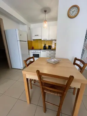 a kitchen with a wooden table and chairs and a clock at MORIANI Plage T2 terrasse proche mer et commerces in Moriani Plage