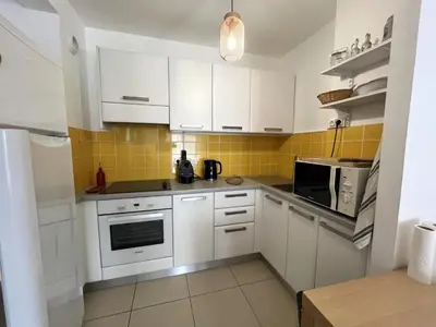a kitchen with white cabinets and yellow tiles at MORIANI Plage T2 terrasse proche mer et commerces in Moriani Plage