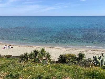 a beach with people sitting on the sand and the ocean at T2 neuf vue mer, piscine chauffée N194 in Linguizzetta