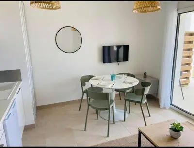 a dining room with a table and chairs and a mirror at T2 neuf vue mer, piscine chauffée N194 in Linguizzetta