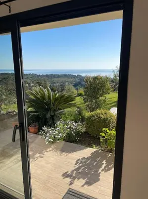 a sliding glass door with a view of a garden at Rez de villa Machja vue mer et montagne à 2mn port in Sari Solenzara