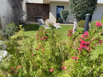 a garden with two chairs and pink flowers at Rez de villa Machja vue mer et montagne à 2mn port in Sari Solenzara