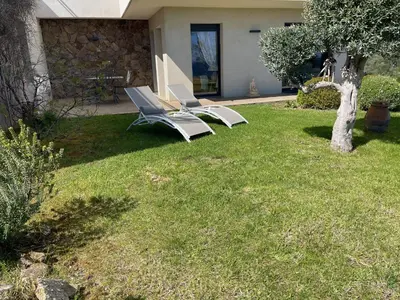 two lounge chairs on a lawn in front of a house at Rez de villa Machja vue mer et montagne à 2mn port in Sari Solenzara