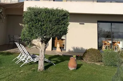 a tree and chairs in front of a house at Rez de villa Machja vue mer et montagne à 2mn port in Sari Solenzara