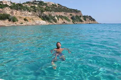 a person in the water in front of an island at Rez de villa Machja vue mer et montagne à 2mn port in Sari Solenzara