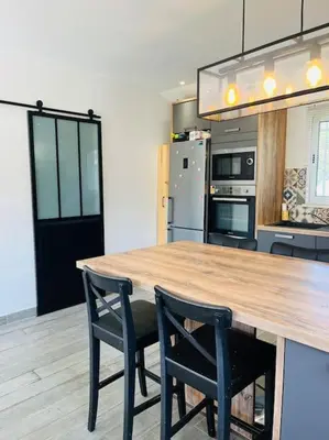 a kitchen with a wooden table and two chairs at Charmante Villa avec Piscine in Appietto