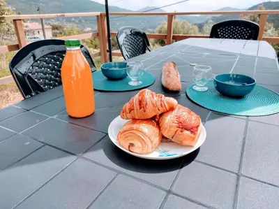 a table with a plate of pastries and a bottle of orange juice at Villa A Funtanella 100m2, paisible, vue mer in Conca