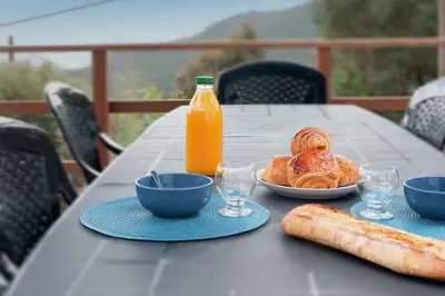 a table with a plate of food and a bottle of orange juice at Villa A Funtanella 100m2, paisible, vue mer in Conca