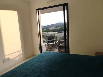 a bedroom with a bed and a sliding glass door at Magnifique T2 neuf à 100 m de la plage d'agosta in Albitreccia