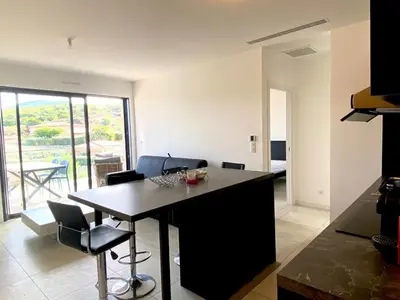 a kitchen and living room with a table and chairs at Magnifique T2 neuf à 100 m de la plage d'agosta in Albitreccia
