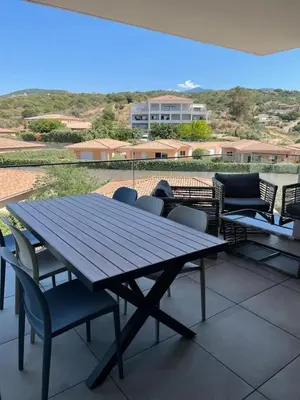 a wooden table and chairs on a patio at Magnifique T2 neuf à 100 m de la plage d'agosta in Albitreccia