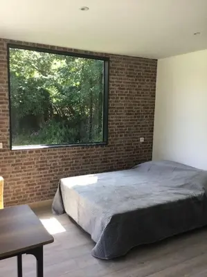 a bedroom with a bed and a large window at chalet 19m2 pour 2 personnes in Omessa