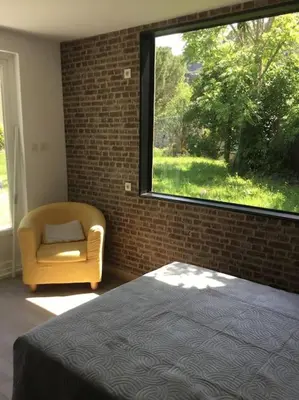 a bedroom with a bed and a chair and a window at chalet 19m2 pour 2 personnes in Omessa