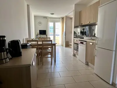 a kitchen with a table and a white refrigerator at Appartement Vue Mer in Sari Solenzara