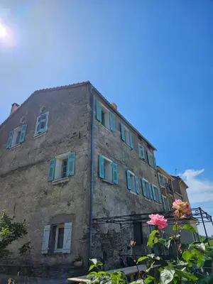 an old stone building with blue windows and flowers at A Casa Di a Vita in Rapale