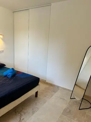a bedroom with a bed and a white wall at La maison du Soleil in Porticcio