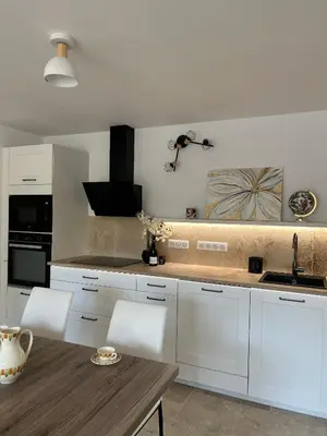 a kitchen with white cabinets and a wooden table at La maison du Soleil in Porticcio