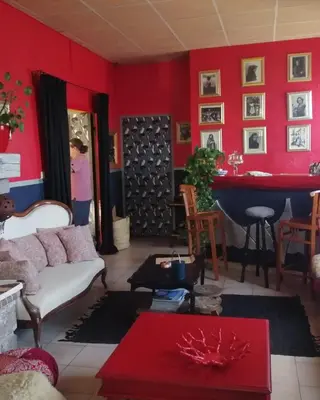 a woman standing in a living room with a red wall at Mountain Lodge Corse Odyssée in Quenza