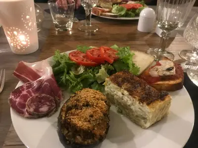 a white plate of food with vegetables and meat at Mountain Lodge Corse Odyssée in Quenza