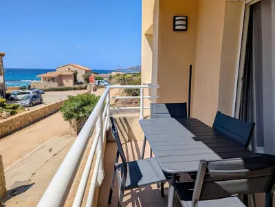 a table and chairs on a balcony with a view of the ocean at Appartement T2 bord de plage in Sartène